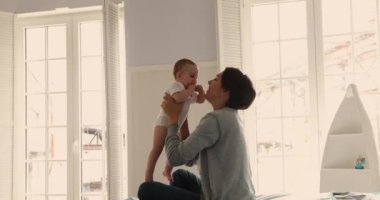 Güzel, sevgi dolu anne yeni doğmuş tatlı bir bebekle yatak odasında oynuyor.