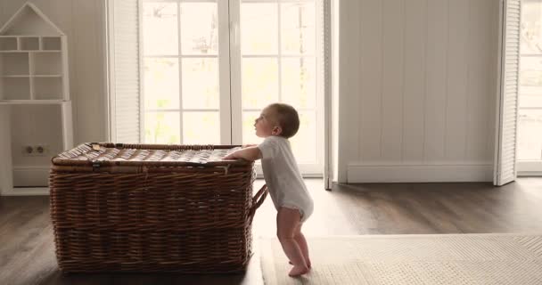 Baby maakt eerste stappen staande leunen op rieten opbergdoos — Stockvideo