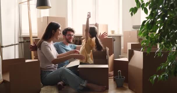 Daughter jumping out carton box celebrate relocation day with parents — Wideo stockowe