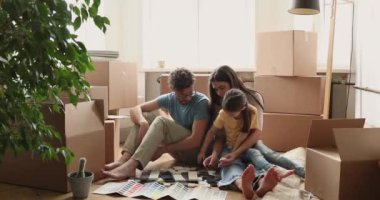 Couple and daughter sit near boxes choose tile swatches color