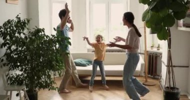 Young couple and cute little daughter dancing in living room