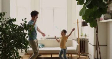 Young father dancing in living room with little cute daughter