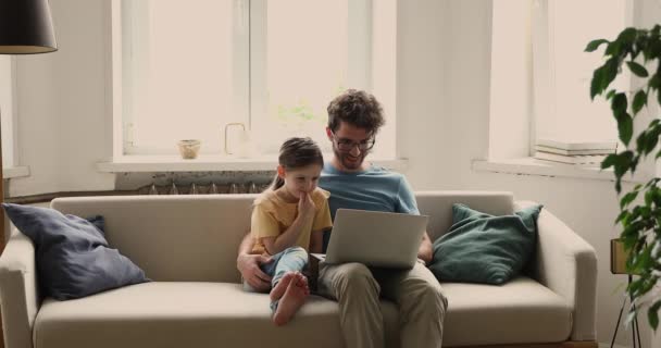 Papá y su hija utilizan el ordenador portátil ver dibujos animados educativos en casa — Vídeos de Stock