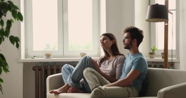 Millennial couple relaxing on cozy sofa discussing room remodelling — Wideo stockowe
