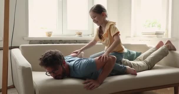 Little girl sits on daddy back playing together at home — Stockvideo