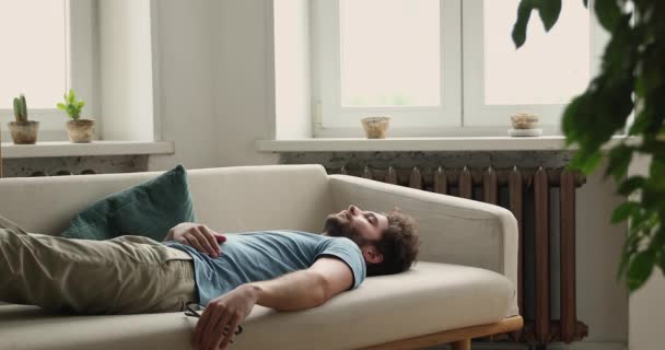 Young man sleeping lying on back on sofa at home — Stock video