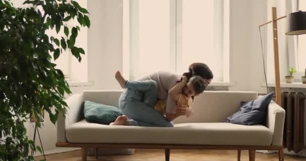 Mother her little daughter hugging sit on cozy sofa — Stock video