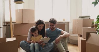 Family resting on floor on relocation day use digital tablet