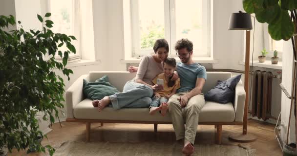 Οικογένεια κάθονται σε καναπέ με κινητό τηλέφωνο απολαύσετε νέα εφαρμογή για κινητά — Αρχείο Βίντεο