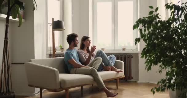 Renters couple talking seated on sofa in living room — 图库视频影像