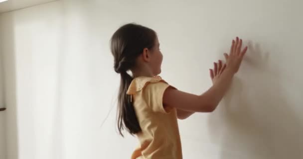 Little cute playful girl catches the reflection of sunlight indoor — 비디오