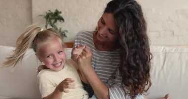 Close up of happy cheerful mom tickle her adorable daughter