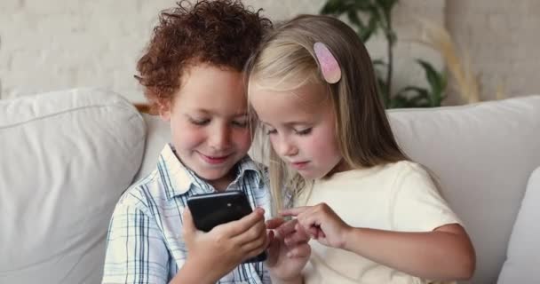 Preschool kids sit on couch at home use smartphone — Vídeo de stock