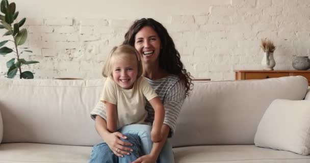Mujer su pequeña hija disfrutar de tiempo de juego sentarse en el sofá interior — Vídeos de Stock