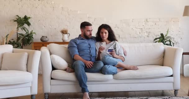 Pareja joven haciendo compra en línea uso tarjeta de débito y teléfono celular — Vídeo de stock