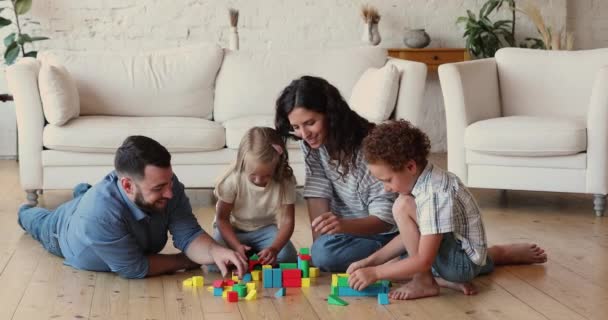 Loving parents play bricks with cute preschool son and daughter — стоковое видео