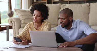 Afro American spouses calculate bills by laptop at home office