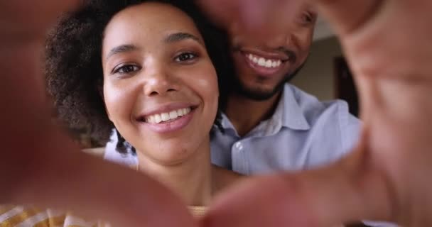 Enamored Black couple look at camera through heart of fingers — Vídeo de Stock