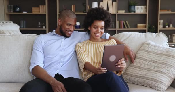 Ευτυχισμένοι νέοι Μαύροι σύζυγοι ξεκουράζονται στο σπίτι με ψηφιακή ταμπλέτα — Αρχείο Βίντεο