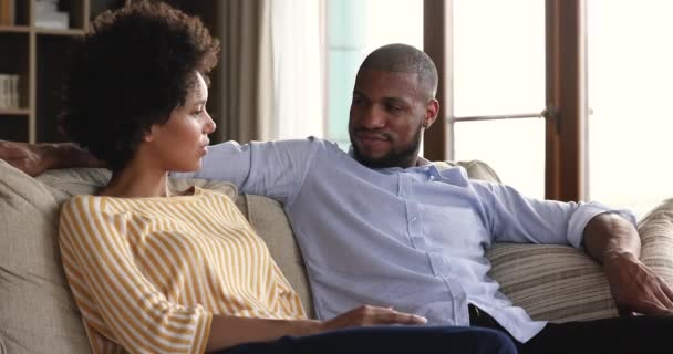 Amistosos jóvenes afroamericanos cónyuges hablando sentados en cómodo sofá — Vídeos de Stock