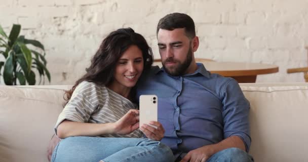 Весела пара використовує мобільний телефон, щоб читати новини соціальних мереж відчувати себе щасливим — стокове відео