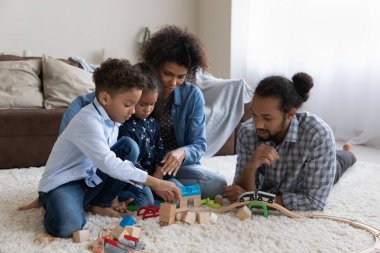 Happy young parents and two kids constructing building wooden blocks
