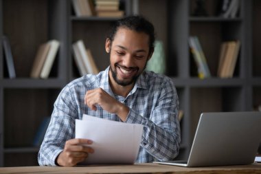 Happy cheerful African student guy reading admission letter from school