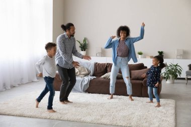 Cheerful excited active African family dancing to music, going wild