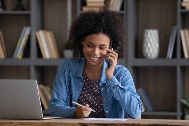 Happy Black freelance employee speaking to client on mobile phone