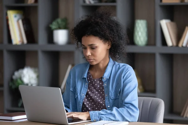Serious young African business woman in casual using laptop — Stock Photo, Image