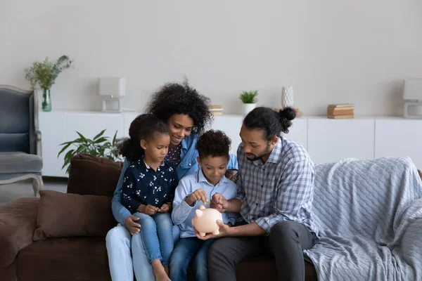 Happy African American parents teaching sibling kids to save money