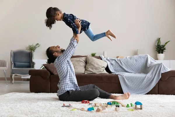 Cheerful Black dad lifting little preschool daughter up in air — Stockfoto