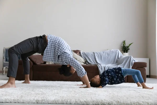 Active Black dad teaching preschool daughter to hold bridge stand — Fotografia de Stock