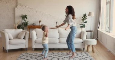 Latina woman dancing with little daughter in living room