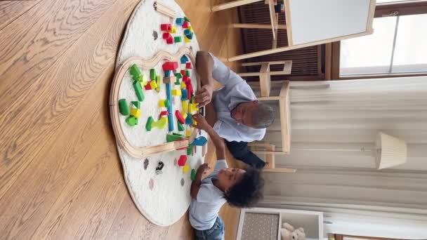 Black dad and son building from toy constructor at playroom — Stock video