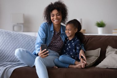 Happy Black mom and cheerful kid taking selfie on smartphone