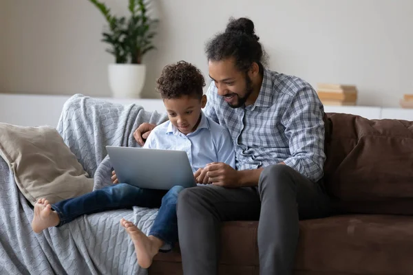 Happy young Black dad and 7s son boy using laptop — Zdjęcie stockowe