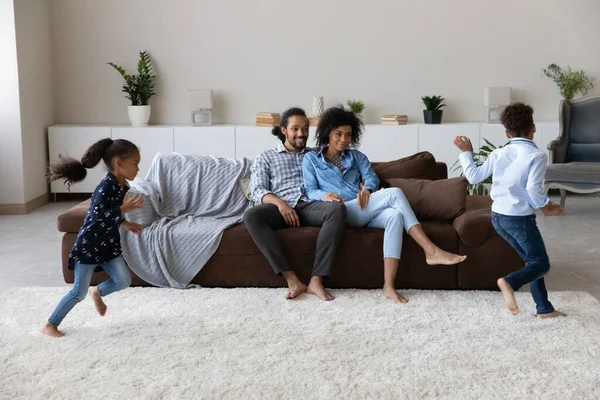 Happy couple of parents watching two energetic hyperactive little kids — Stock fotografie