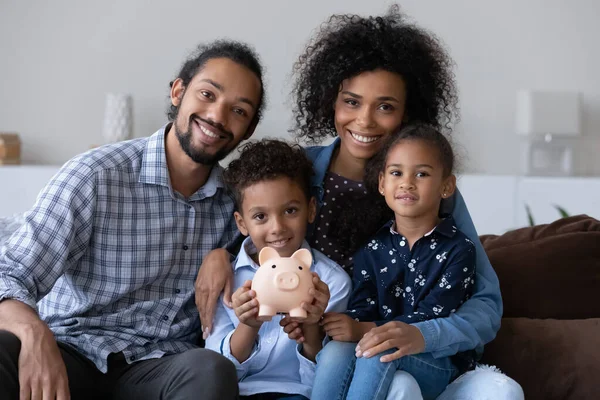 Happy Black family couple and little kids making financial reserve — стоковое фото