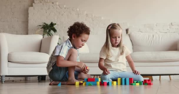 Cute children sit on floor at home play wooden cubes — Vídeo de Stock