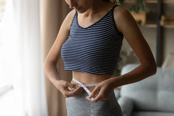 Fit strong young woman measuring waist with tape. — ストック写真