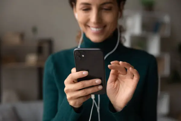 Happy young woman in wired earphones using smartphone. — 图库照片