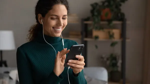 Happy young beautiful woman in earphones using smartphone. — Stock Photo, Image