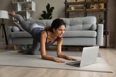 Happy attractive millennial woman training online at home.