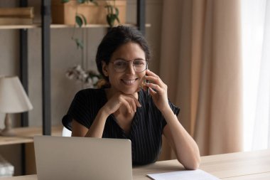 Smiling young pretty woman multitasking at home office.