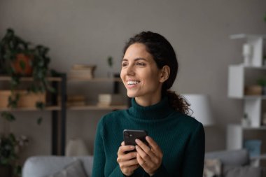 Dreamy young woman using smartphone software applications.