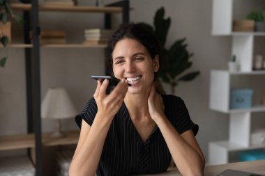 Happy attractive millennial woman sending mobile voice message.