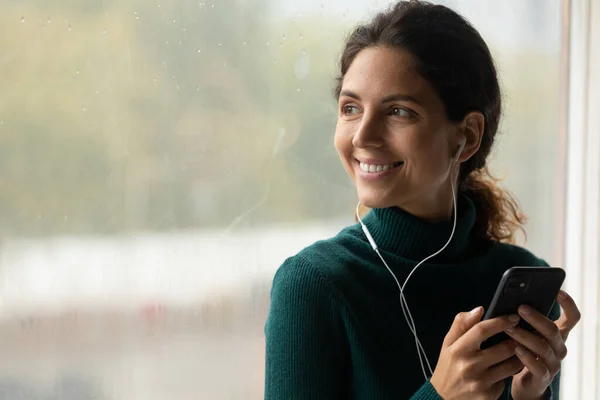Dreamy peaceful woman listening music, standing near window. — Stockfoto