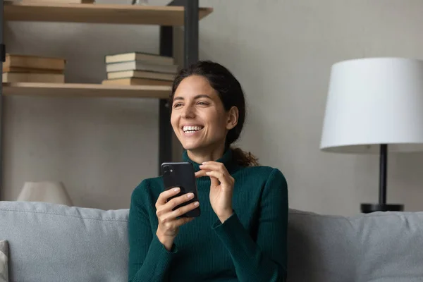 Mujer joven feliz entretenida usando el teléfono inteligente en casa. — Foto de Stock