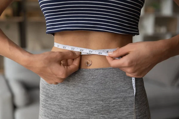 Acercamiento deportivo en forma de mujer joven que mide la cintura con cinta. —  Fotos de Stock